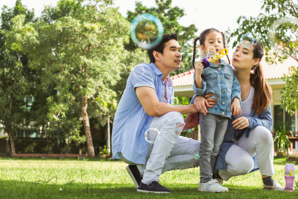 felice famiglia asiatica che gioca in giardino soffia bolla, felice e sorriso - park child asia lifestyles foto e immagini stock