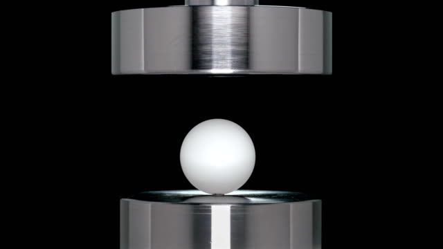 the ball from table tennis is crushed by hydraulic press, close-up