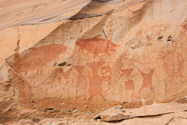 istock Fantastic ancient paintings on sandstone cliff, 3,000 year-old. Scene in paintings include giant Mekong catfish, elephants, turtles, rice farming, human figures, hands and geometric designs. Pha Taem National Park, Thailand. Soft sunlight. 1066238904