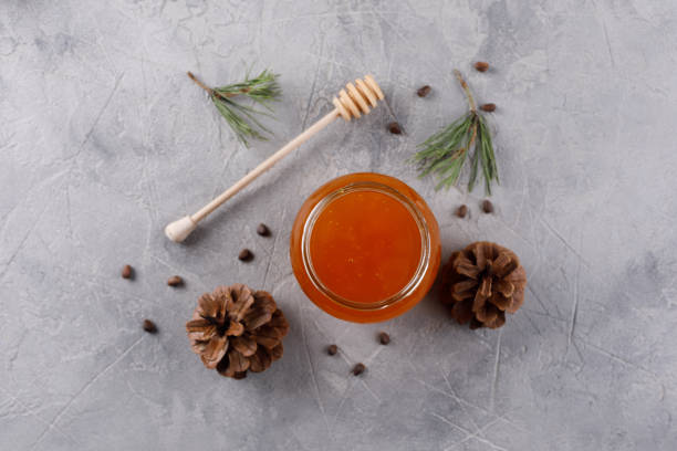 Honey in a glass jar. Set against colds with pine nuts conifer and pine cones. stock photo