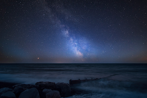Stunning vibrant Milky Way composite image over landscape of pier at sea in Worthing England