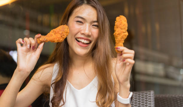 primo piano giovane donna asiatica tenendo pollo fritto con sensazione felice al ristorante esterno per il concetto di giorno speciale - deep fried people fried chicken foto e immagini stock