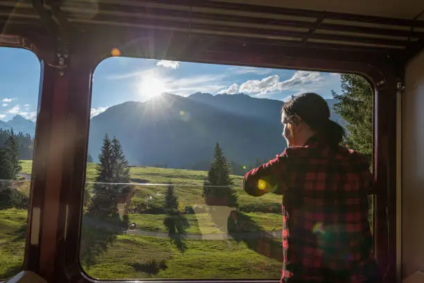 Photo of Woman looks out window of moving rail coach, on railway