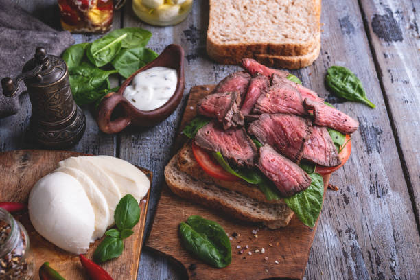 istock Steak sandwich, sliced roast beef, cheese,spinach leaves,tomato. Rustic,on a wooden surface 1066286668