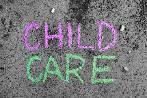 Colorful chalk drawing on asphalt: words CHILD CARE