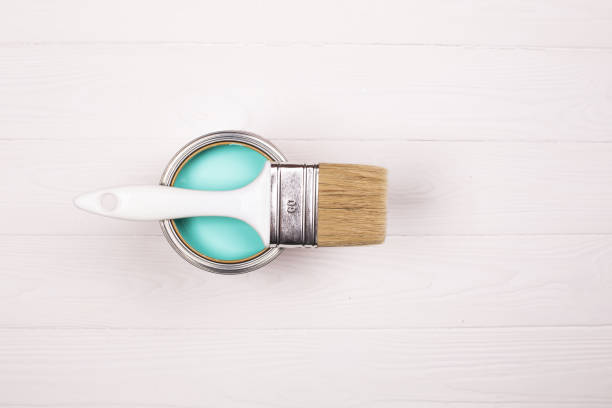 istock Open blue paint can and white brush on white wooden background. 1066301510