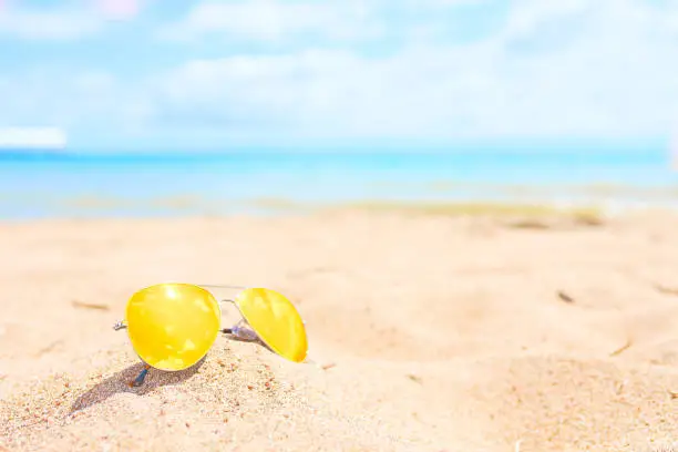 Yellow sunglasses on the beach. Resort concept