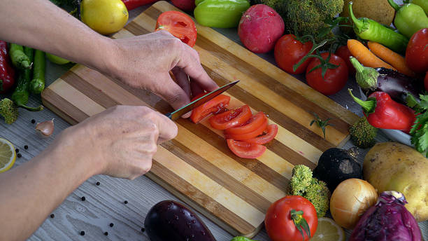 istock Man is cutting vegetables in the kitchen, slicing tomato in slow motion 1066310552