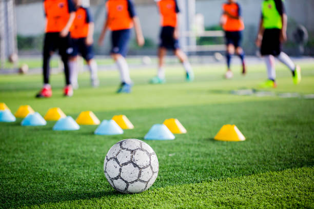 istock Soccer ball on green artificial turf with blurry of maker cones and player training 1066313236