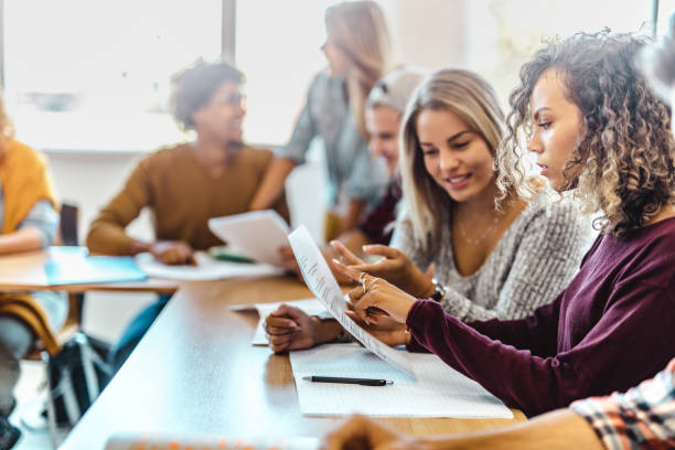 istock Female student cooperating with her friend while studying in classroom. 1066320044