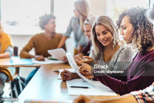 Female Student Cooperating With Her Friend While Studying In Classroom Stock Photo - Download Image Now