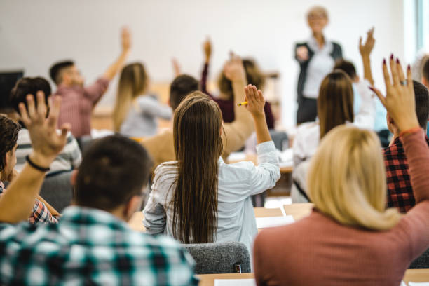 istock Back view of college students raising their arms on a class at lecture hall. 1066323096