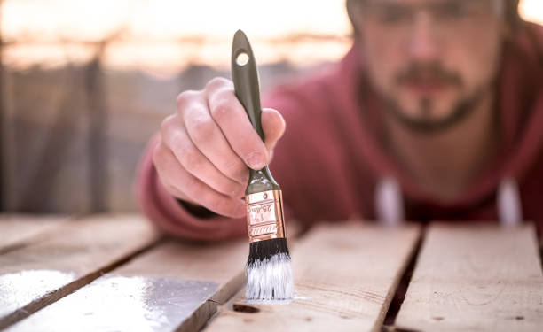 istock man paints with white paint on wooden planks 1066326596