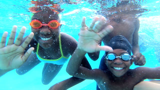 Multi-ethnic children underwater waving at camera