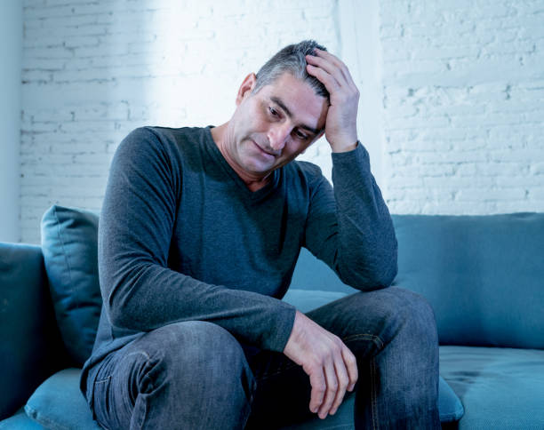 istock Attractive man feeling desperate sad looking worried depressed thoughtful and lonely suffering depression on couch at home in middle age crisis mental health personal problems and life style concept. 1066347674