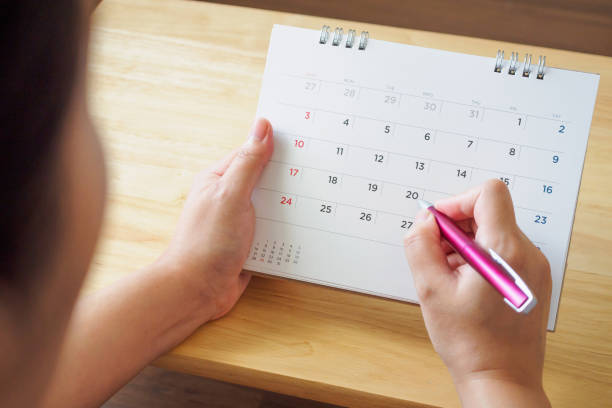 istock calendar page with female hand holding pen on desk table 1066357942