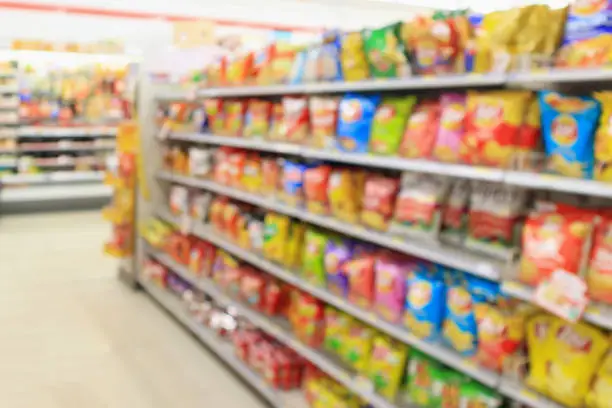 Photo of Supermarket convenience store shelves with Potato chips snack blur abstract background