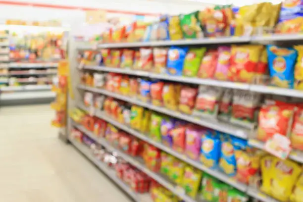 Supermarket convenience store shelves with Potato chips snack blur abstract background