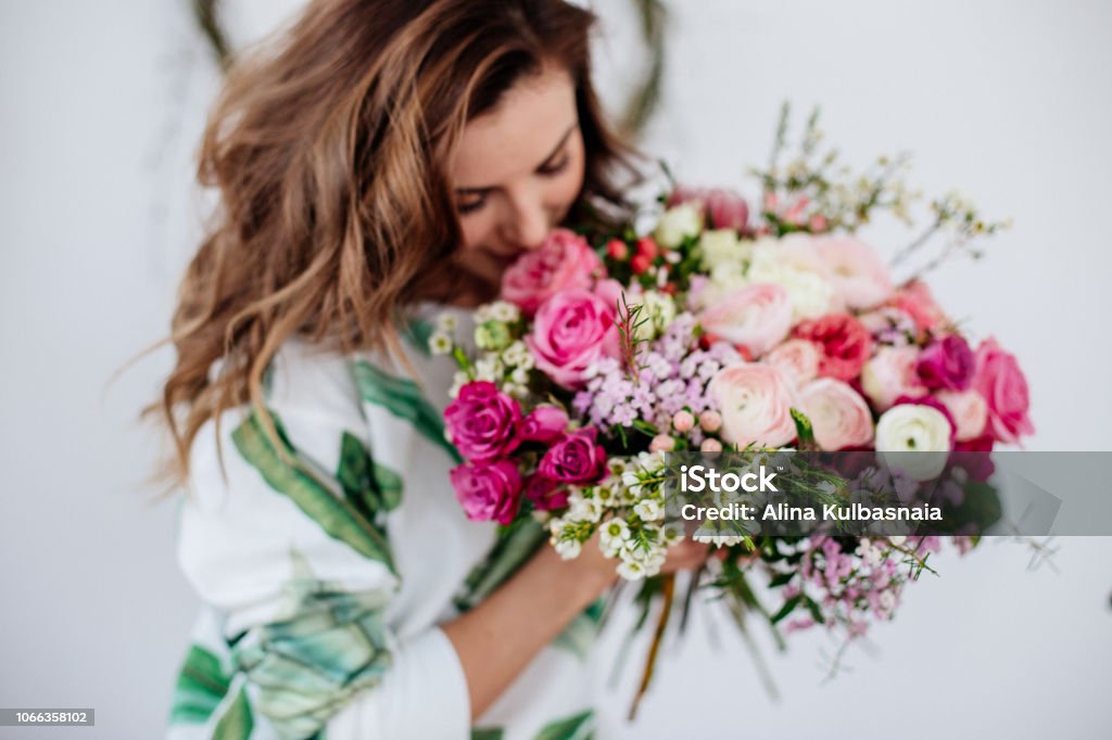 Florist makes a bouquet. A girl florist makes a bouquet in a light studio on a wooden table. Flower Stock Photo
