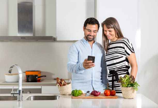 istock couple in a kitchen checking messages in their phone 1066365276
