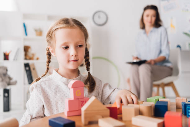 istock adorable little child playing with blocks while psychologist sitting blurred on background 1066365752