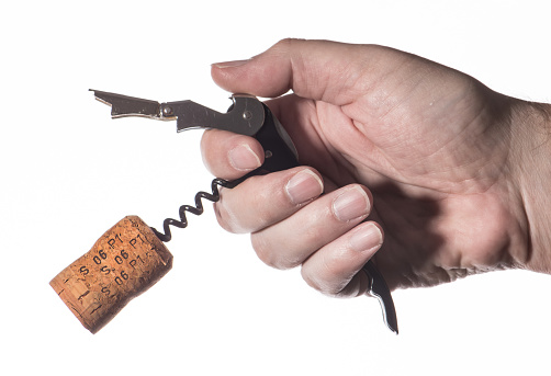 Male hand opens a bottle of wine. Cork and corkscrew.