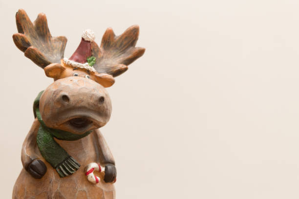 Christmas time. Wooden moose with santa hat holding a candy cane. Left side on a white background. Copy Space. Christmas Card. Front view