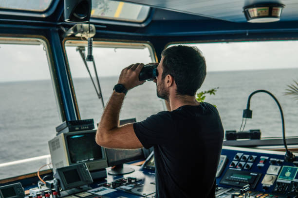 istock Navigational officer lookout on navigation watch looking through binoculars 1066380692