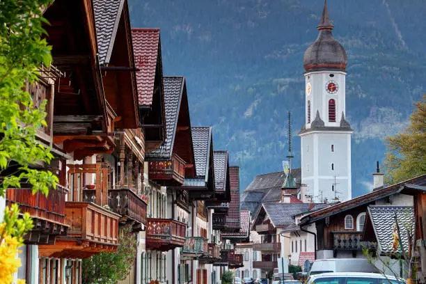 Photo of Row of traditional German houses with wooden balconies with Parish Church St. Martin in Garmisch Bayern Germany