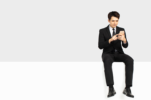 businessman watching smart phone and sitting on blank panel