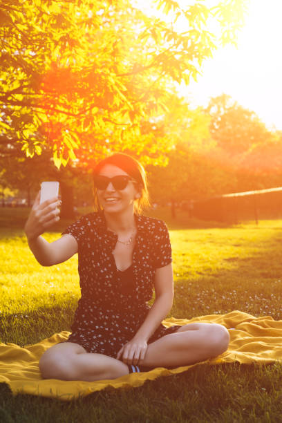 istock Young woman sitting in the park, using her phone 1066387344