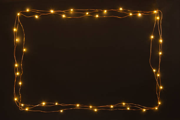Christmas lights garland border over black background. Flat lay, copy space.