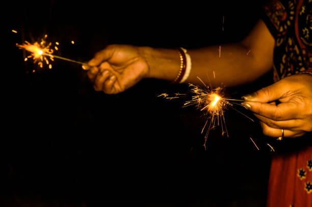 istock Sparklers on hand on black background on a low light evening. 1066410238