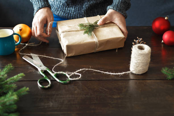istock Male hands wrapping christmas gift wooden table 1066432770