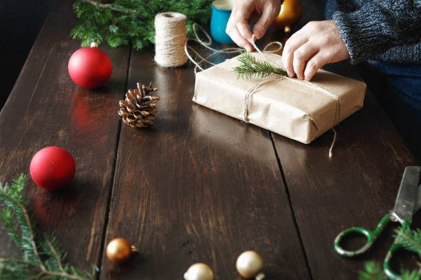 istock Male hands wrapping gift box wooden table Rustic Christmas presents background 1066433530