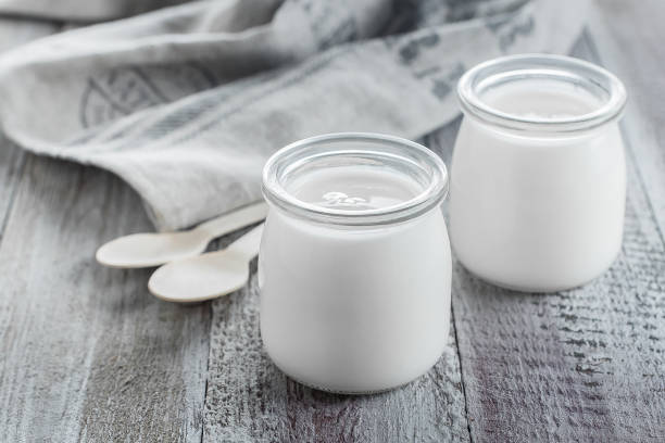 yogurt greco in barattoli di vetro con cucchiai di legno su sfondo di legno. cibo per la colazione sano. spazio di copia - morning cream food milk foto e immagini stock