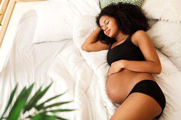 Pregnant woman sleeping in bedroom at home stock photo
