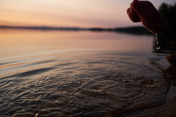 istock Human hand trying to touch the fresh water from lake 1066445748