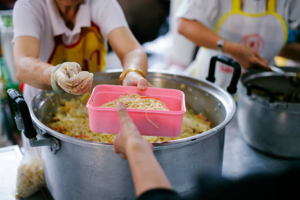 istock Volunteers provide food for beggars: Concepts Feeding and help 1066447690