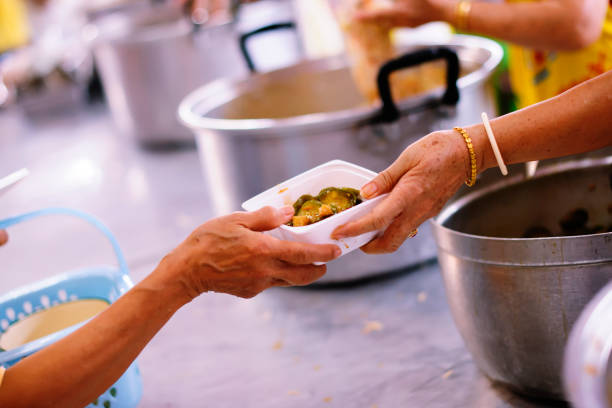 istock Volunteers provide food for beggars: Concepts Feeding and help 1066447712