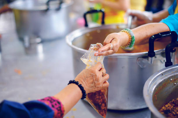 istock Volunteers provide food for beggars: Concepts Feeding and help 1066447916