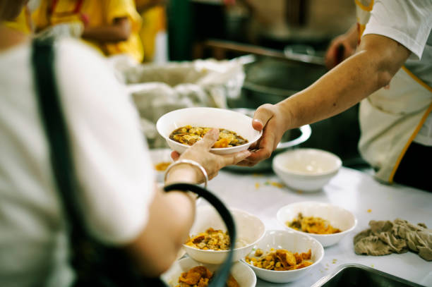istock Volunteers provide food for beggars: Concepts Feeding and help 1066448354