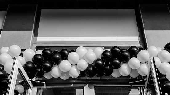 Black and white photo. Many balloons at opening of supermarket