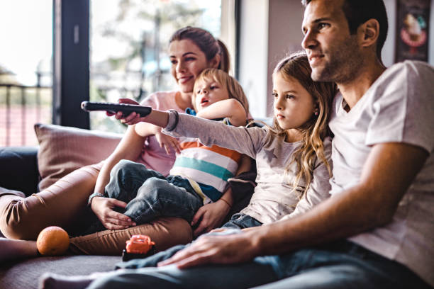 istock Young parents enjoying with their small kids on sofa while watching TV together. 1066465150