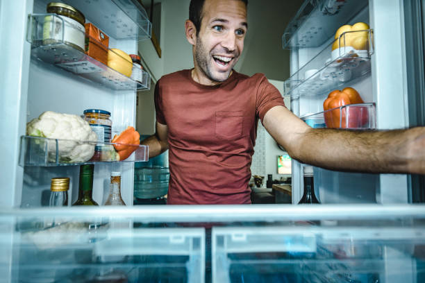 istock Happy man taking food from a fridge in the kitchen. 1066470212