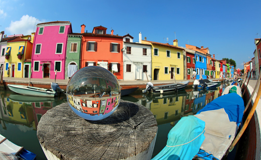 colorful houses on the island of Burano near Venice in Italy and a large glass sphere with the reflection of the village