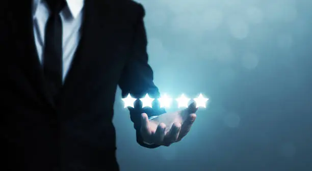 Photo of Businessman hand holding five star symbol to increase rating of company concept