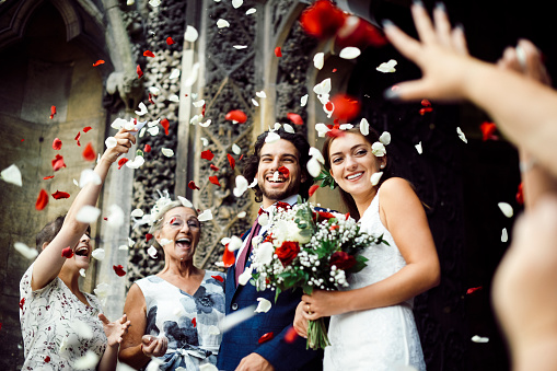Familia lanzando pétalos de rosa en el novio y la novia recién casada photo
