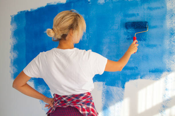 istock woman painting a wall with paint roller 1066487288