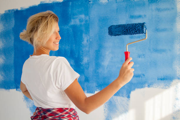 istock woman painting a wall with paint roller 1066487294